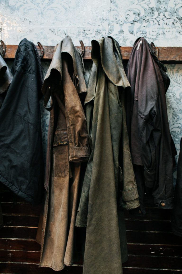 Image of some traditional rain coats that have been well worn, hanging on a coat hanger- a symbol of hard work and dedication to our craft in ironmongery.